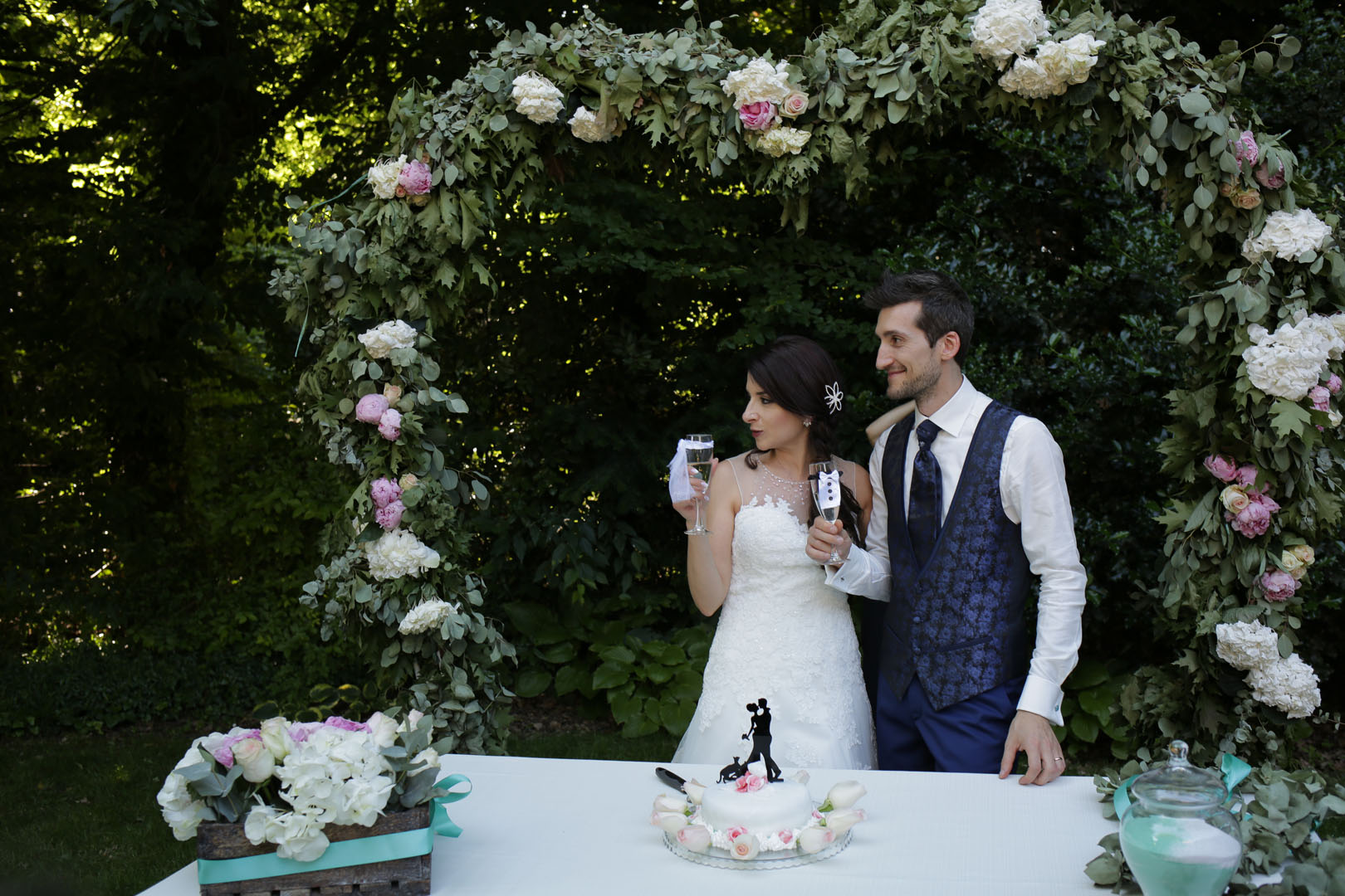 sposi-felici-taglio-della-torta-nel-giardino-dcon-decorazioni-floreali